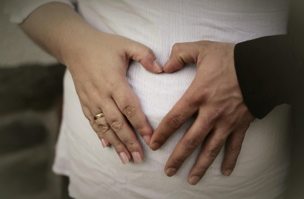 역아 진단 후 태아 자세와 엄마 몸 상태, 자궁 환경을 고민하는 임산부의 배 위 손 하트 모습