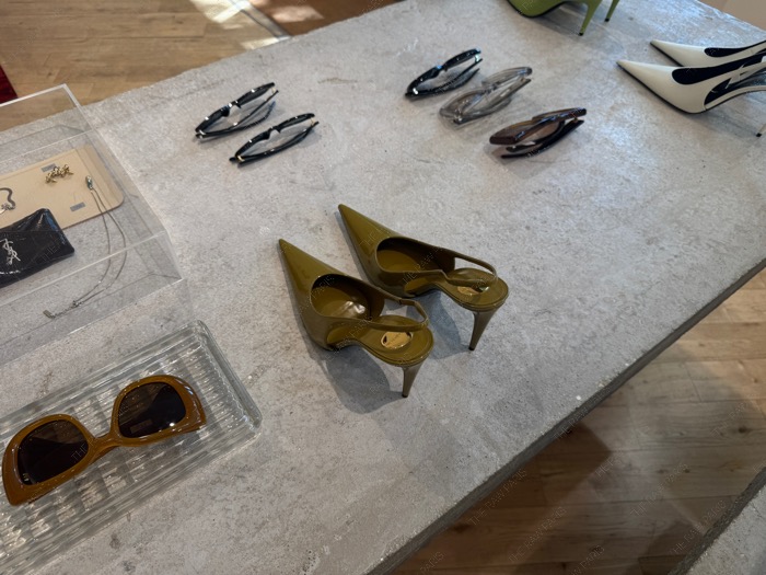 Olive green pointed slingback heels and designer sunglasses on a concrete display table at The Broken Arm ❘ Style The Broken Arm⁠