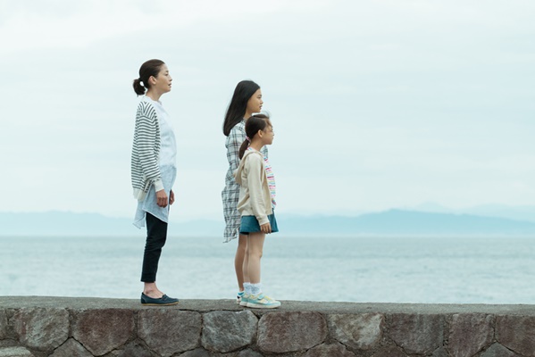 영화 행복 목욕탕에서 주인공 후타바와 두 딸이 바닷가 방파제 위에 나란히 서서 수평선을 바라보며 강인하게 삶을 마주하는 장면