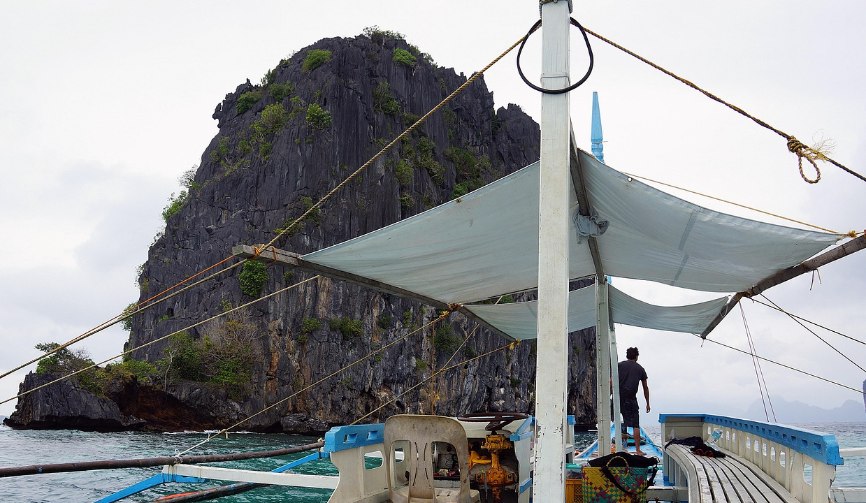 팔라완 엘니도의 석회암 절벽을 배경으로 배가 항해하는 모습의 사진