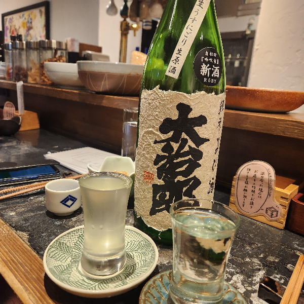 초록색 사케병과 사케 잔 두 개가 놓여 있다.