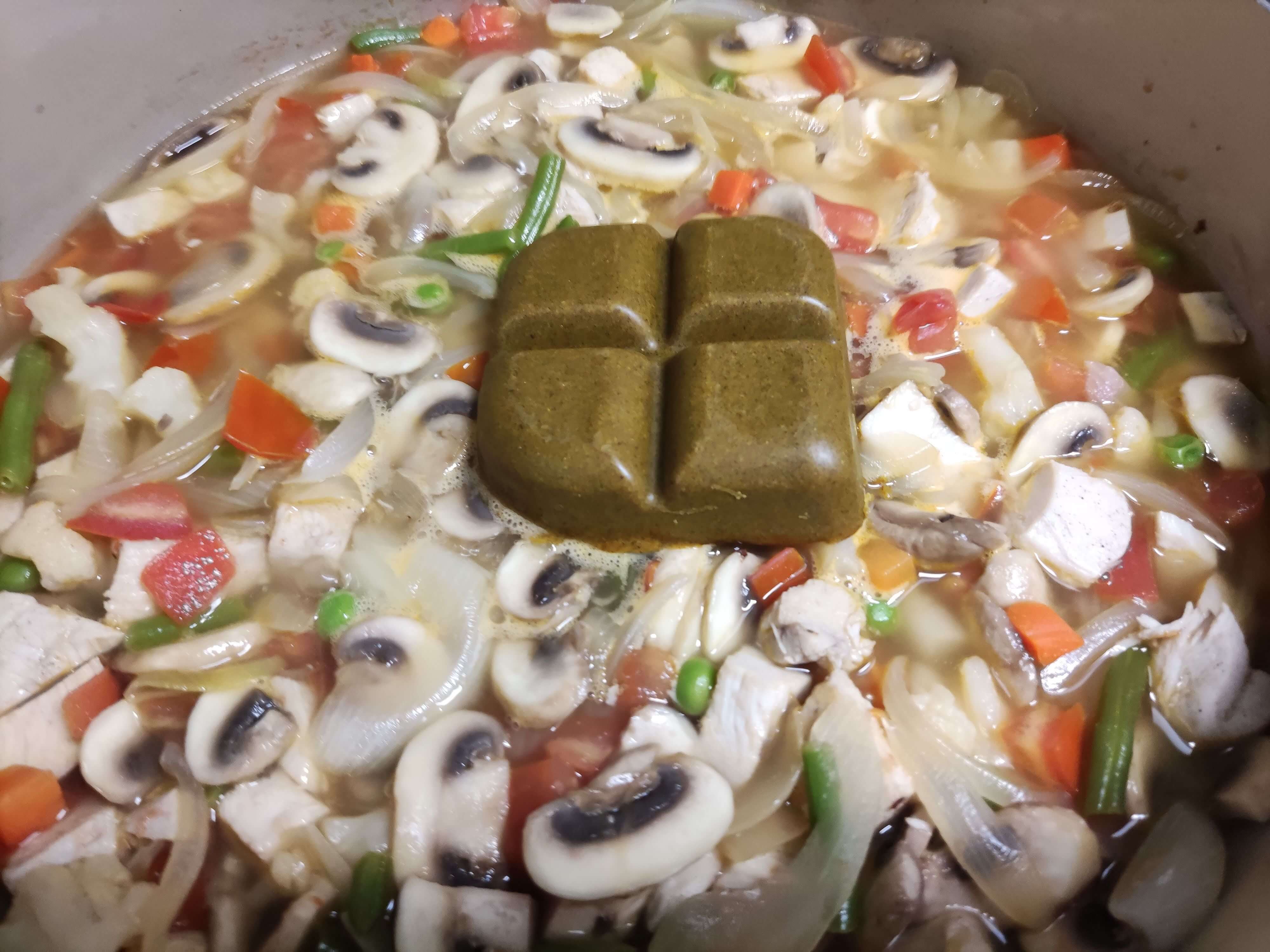 물을 붓고 끓는 카레 재료 위에 고형 카레 큐브를 넣는 모습