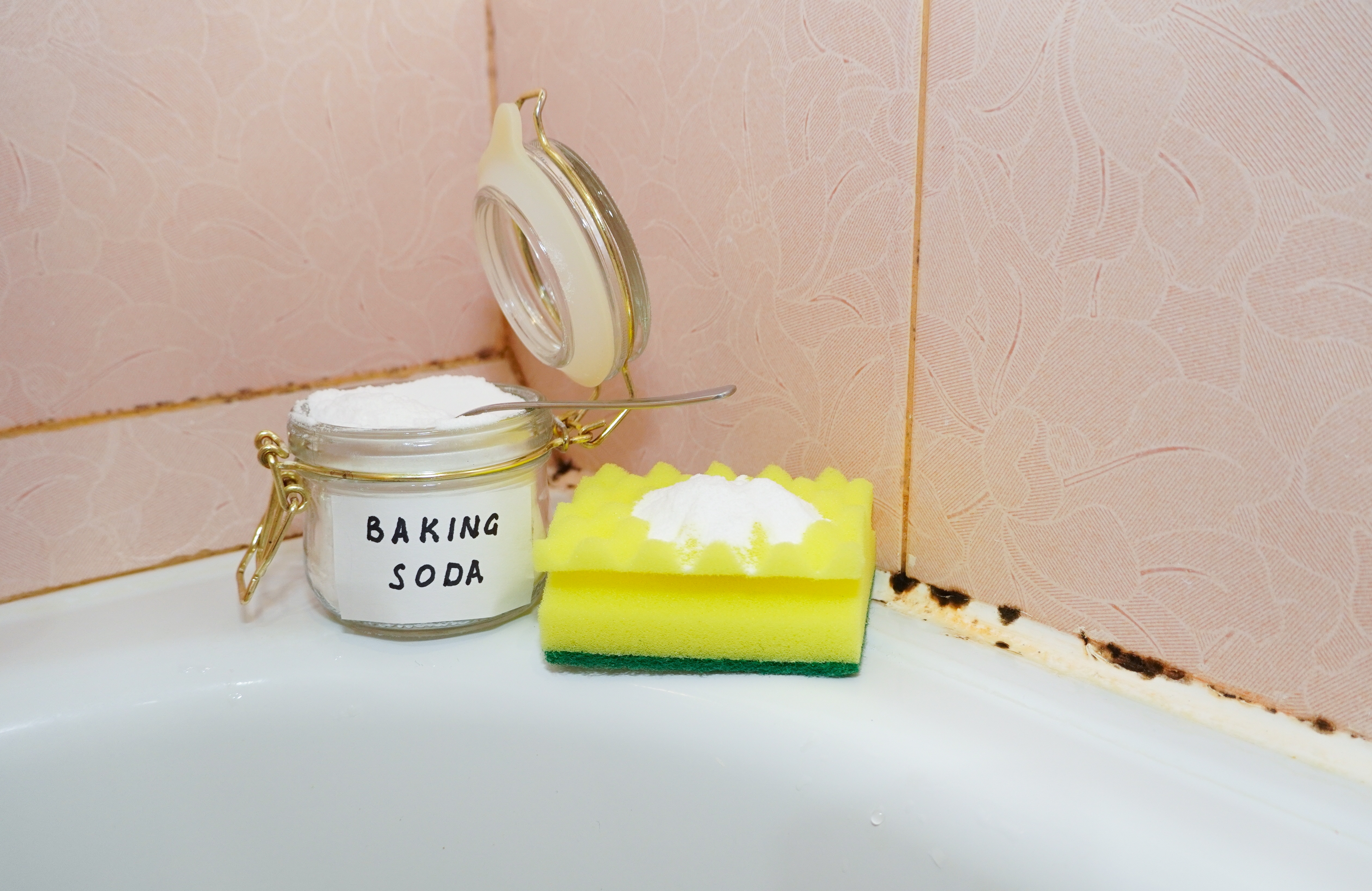 베이킹소다와 스펀지를 활용한 욕실 곰팡이 제거 장면, 천연 재료로 곰팡이 청소하는 모습