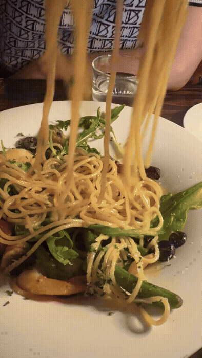 논현동 와인바에서 주문한 쉬림프 알리오 올리오 파스타를 포크로 들어 올리는 장면. 면발이 탱글하게 살아 있고 신선한 채소와 새우가 곁들여져 있다.