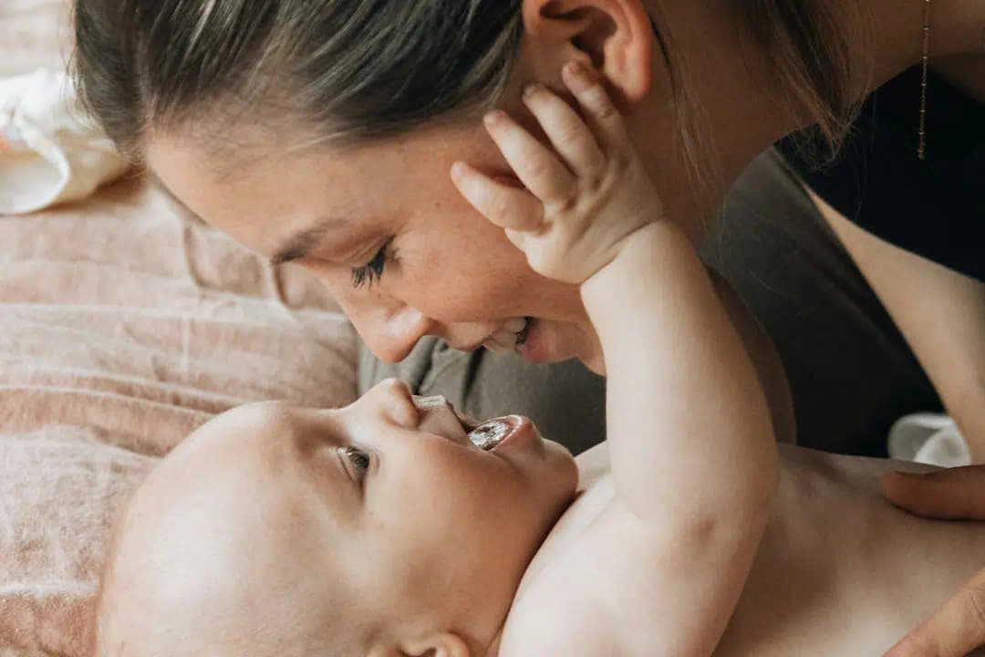 아기와 눈을 마주보는 엄마, 부모급여로 안정된 양육 환경 상징