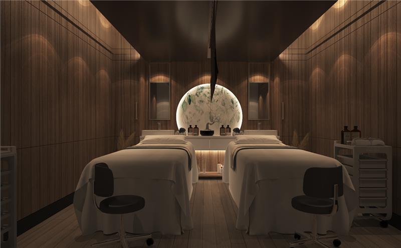 “팬스타미라클호의 웰니스 테라피룸 내부. 어두운 우드톤 벽과 은은한 간접 조명이 아늑한 분위기를 자아내며, 중앙에는 두 개의 마사지 베드가 나란히 배치되어 있다. 뒤편에는 원형 조명 프레임 속 식물 일러스트가 장식되어 있고, 아로마 오일과 테라피 용품이 정돈되어 있다.”