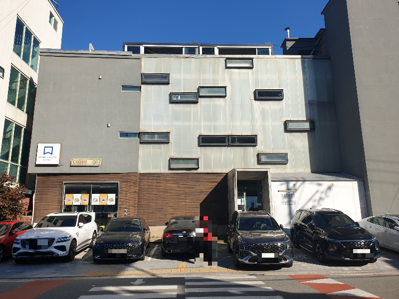 카페 건물 앞에 6대의 차가 주차되어 있다.