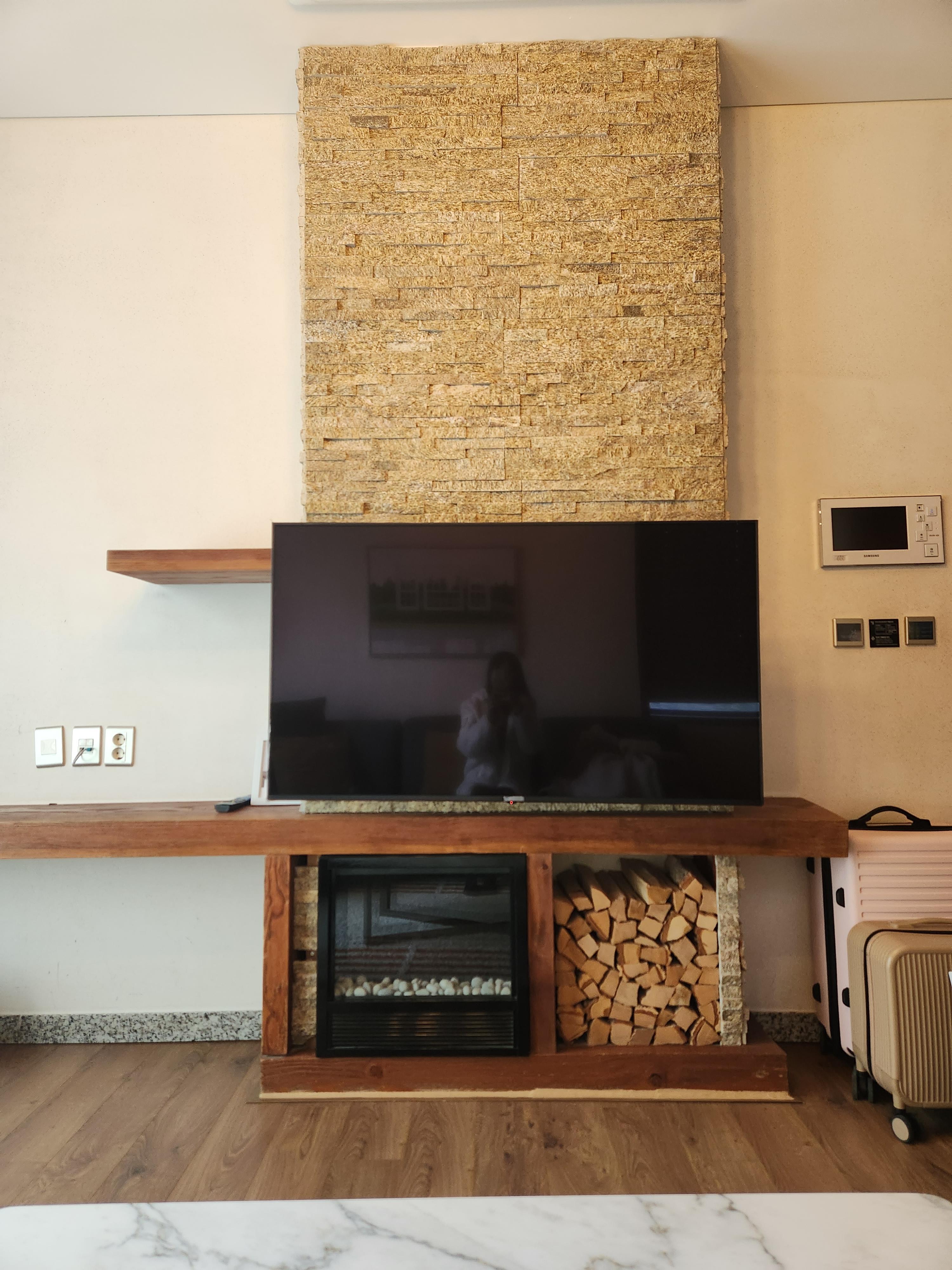 벽돌 장식의 벽과-벽난로-벽난로 안에는 장작이 있고-TV가 놓여있음