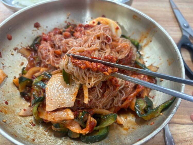 냉면과 홍어회 무침을 젓가락이 함께 집고 있는 사진이다.