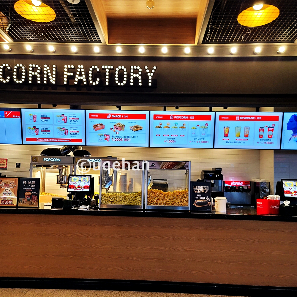 동두천 CGV 영화관 스낵바에서 판매되고 있는 스낵들의 종류와 가격이 안내되고 있고, 테이블위에 팝콘이 판매되고 있다.