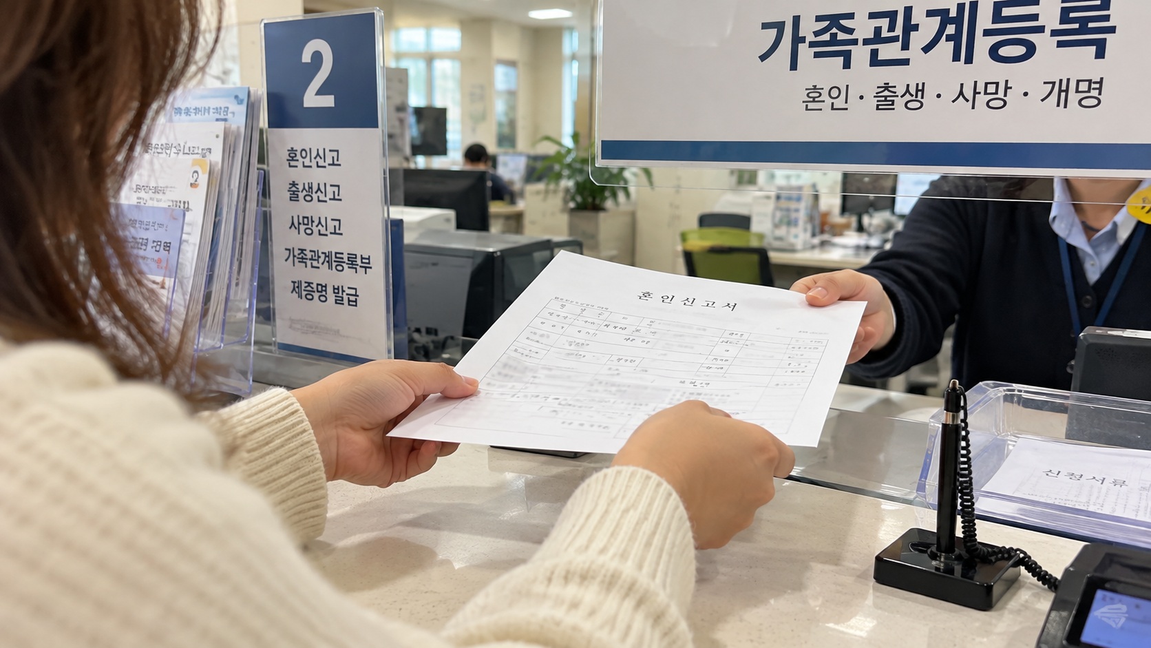 구청 가족관계등록 민원 창구에서 담당자에게 혼인신고서를 제출하는 모습