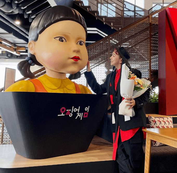 오징어게임2 영희 모형 앞에 한 사람이 서있는 사진