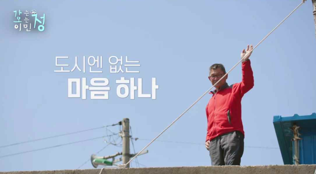 하늘을 배경으로 빨간잠바를 입은 할아버지가 손을 흔드는 장면에 도시엔 없는 마음 하나 자막이 있는 스틸컷