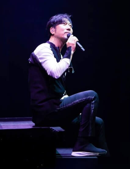 이문세가-무대-계단에-앉아-노래를-하는-옆모습