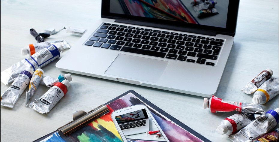 물감들 노트북 휴대폰 스케치북 등이 보이는 사진
