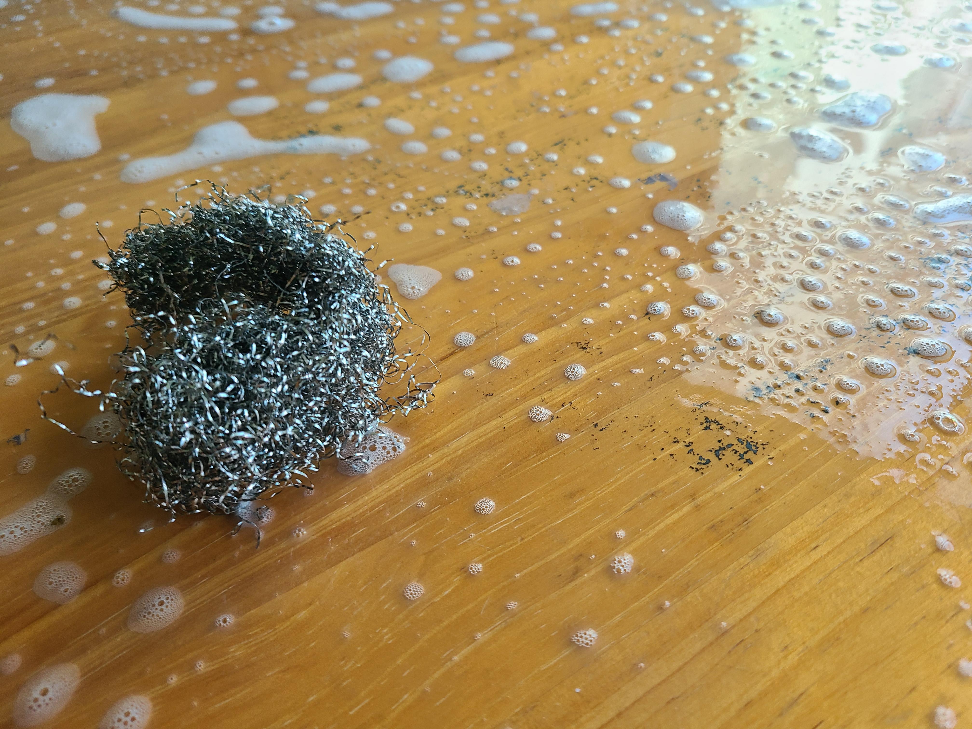 비누거품이 묻은 원목식탁과 철수세미