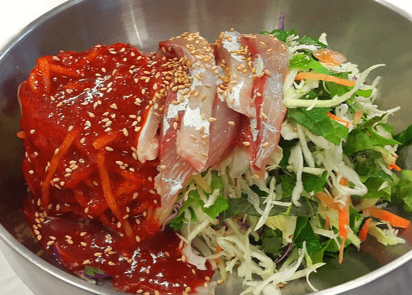 쇠그릇에 회덮밥이 있다. 밥 위에 싱싱한 회와 야채들, 고추장 소스가 가득하다.