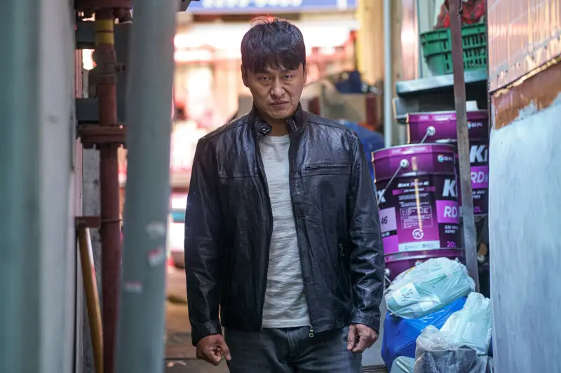 어느 주택가 좁은 골목을 배경으로 무서운 얼굴로 누굴 노려보고 있는 형사 재환