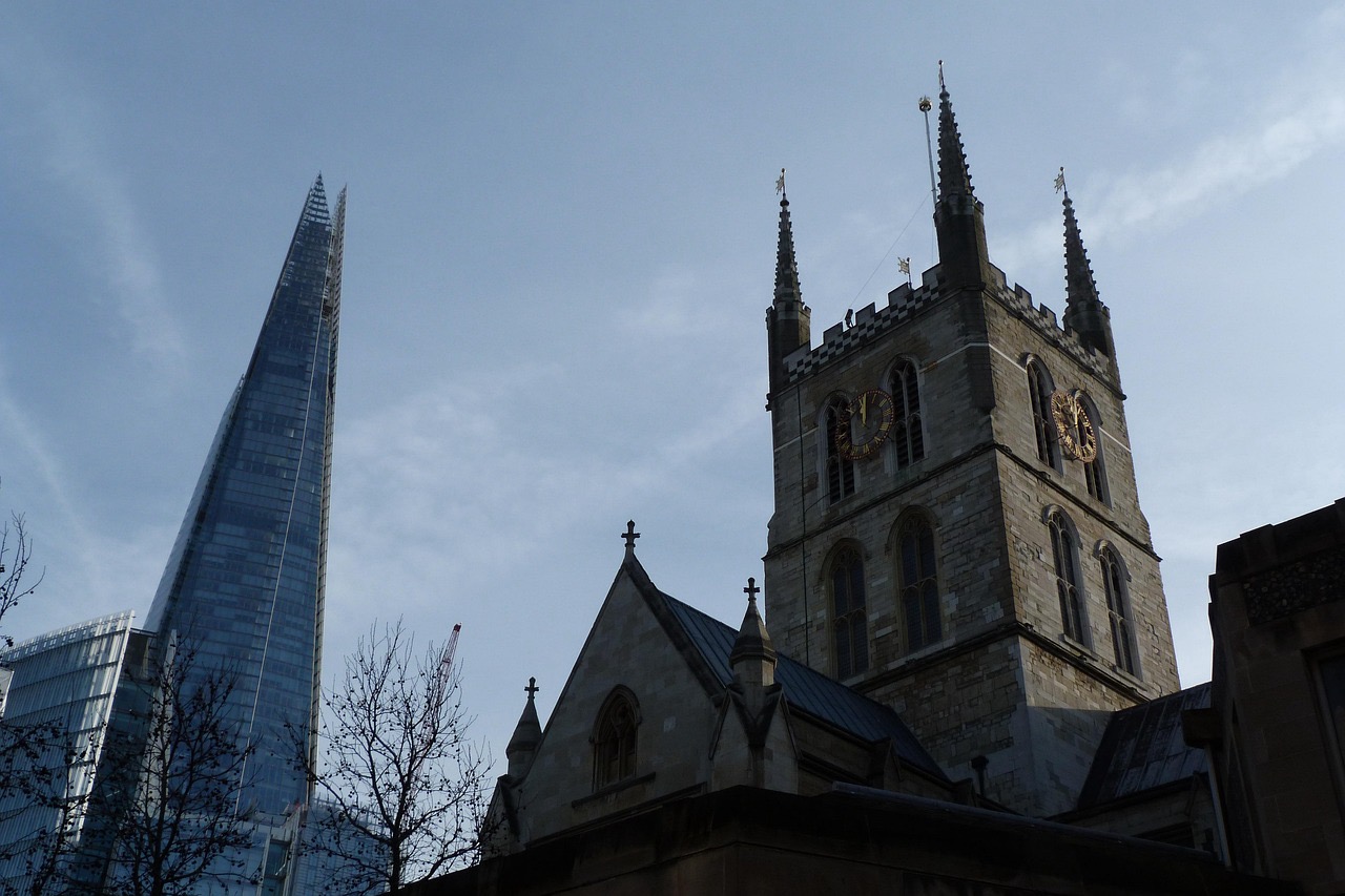 사우스워크 대성당의 고딕 양식 건물과, 그 뒤로 솟은 현대적인 유리 건축물 더 샤드가 나란히 보이는 런던 시내 풍경. 전통과 현대가 공존하는 도시의 조화가 인상적이다.