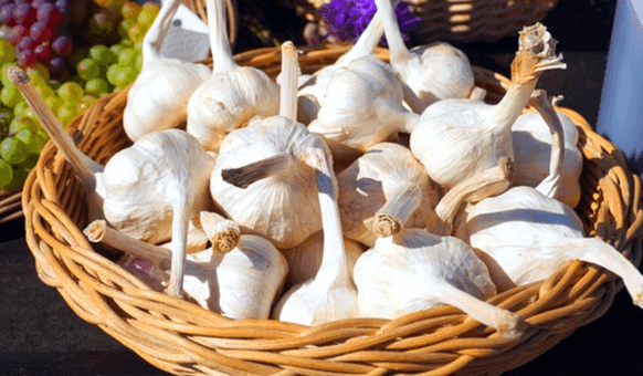갈색 바구니에 하얀색의 통마늘들이 한가득 들어있다. 왼쪽 바구니에는 청포도와 검정포도가 가득하다.