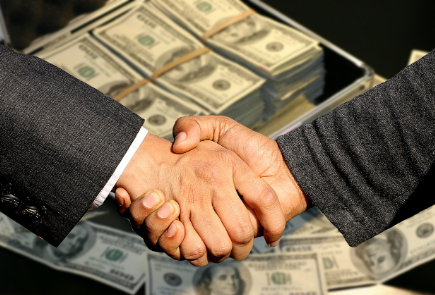 거래와 협상을 나타내는 돈과 악수 이미지