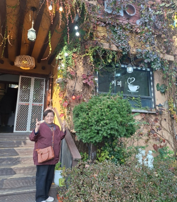 붉은 담쟁이덩굴 건물 앞에서 포즈를 취하고 계신 어머니