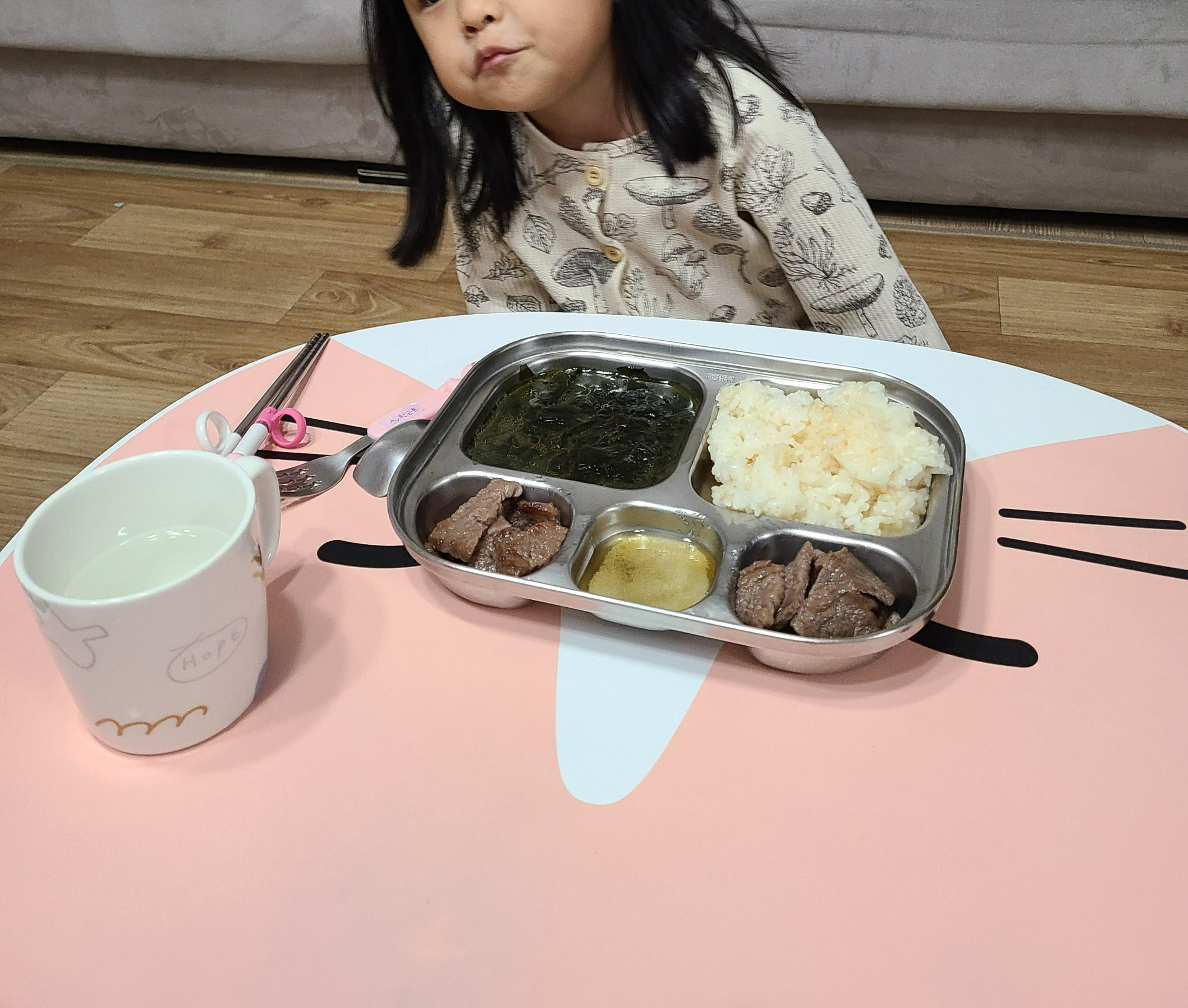 식판과 밥그릇 앞에 앉아 고사리손을 모으고 있는 아이 모습