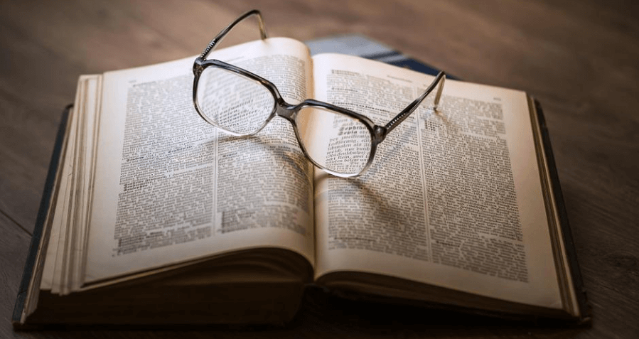 펼쳐진 책 위에 안경이 놓여 있다