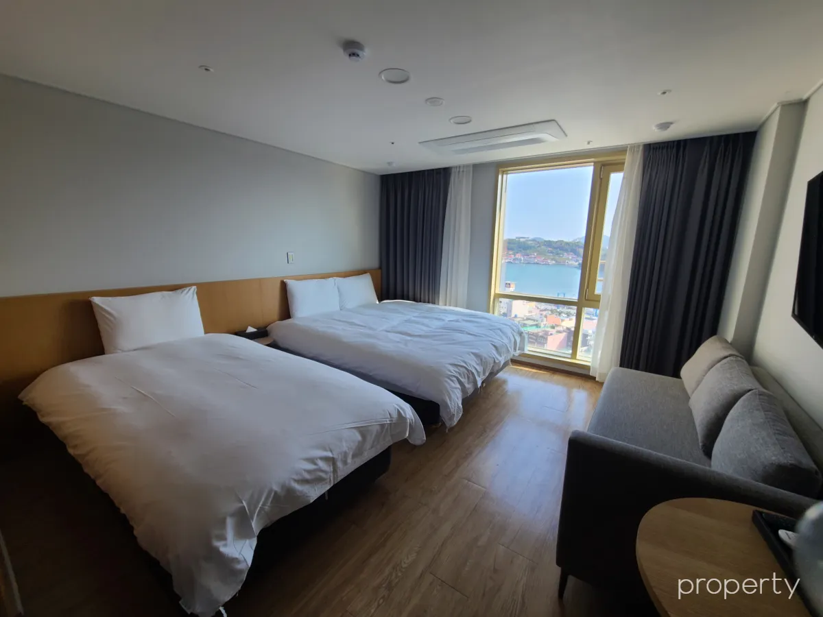 케니호텔객실-베드2개-희색소파-창밖으로보이는바다