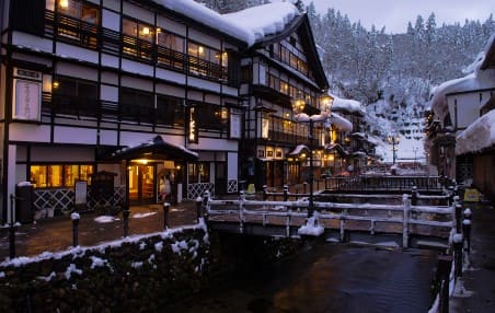 건물이 위에 눈이 쌓여있고 건물안에서 노란색 불빛이 나오고 있다