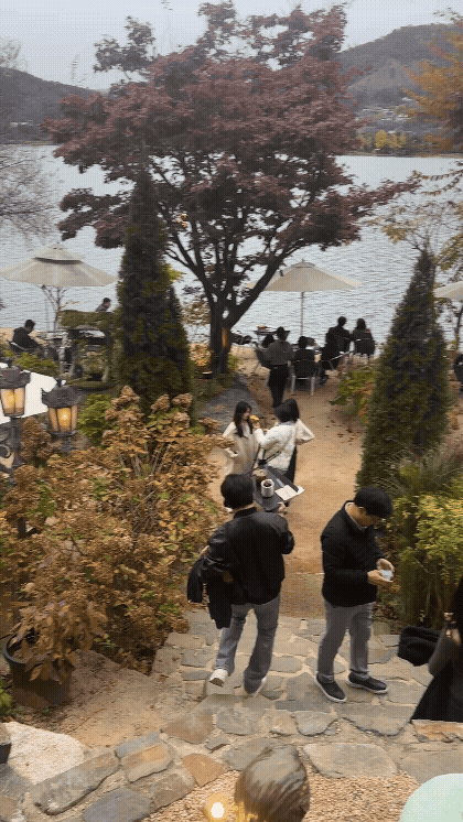 포천 카페 데너리스 뒤쪽 정원으로 내려가는 길gif. 가을 풍경과 북한강 강뷰가 한눈에 보이고, 야외석에서 커피를 즐기는 사람들 모습이 담긴 장면