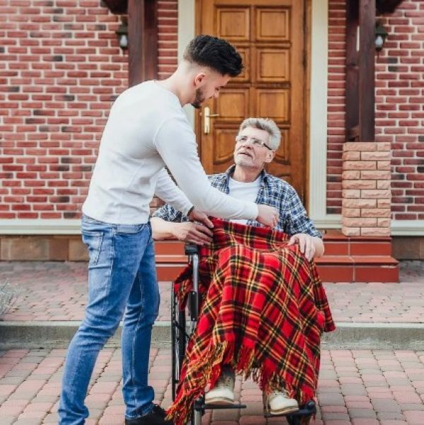 휠체어에 앉은 노인을 돌보는 젊은 남성 요양보호사의 모습