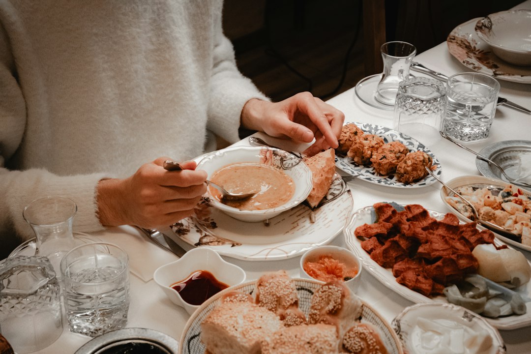 여러 음식이 차려진 식탁에서 수프를 떠먹으며 식사하는 손