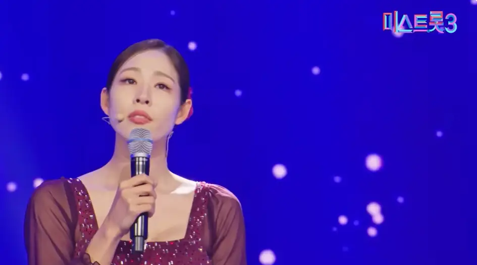 미스트롯3-
불은색 망사드레스를 입고 오른손으로 마이크를 올린채 관중을보고 노래하는 신수지