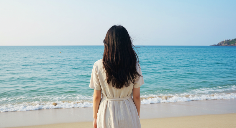 제주 해변에서 파도 소리를 듣는 한국 여성의 평화로운 뒷모습