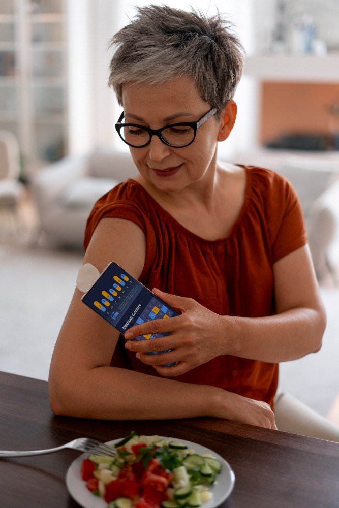 중년 여성이 팔에 부착된 혈당 센서를 확인하며 혈당을 관리하는 모습