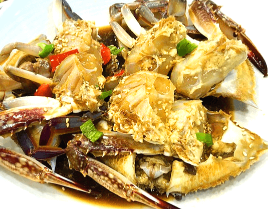 하얀 접시에 간장게장이 한가득 있다. 속살은 간장에 버무려졌고, 썰어진 고추가 가득하다.