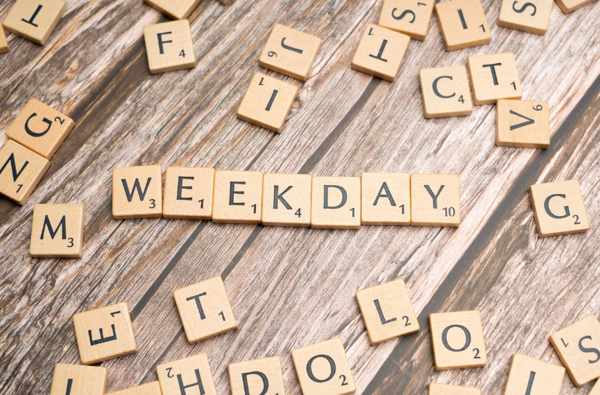 'WEEKDAY'라는 단어가 나무 바닥 위 스크래블 타일로 배열된 모습 - 일상 속 습관 유지를 위한 환경 설계의 중요성을 상징