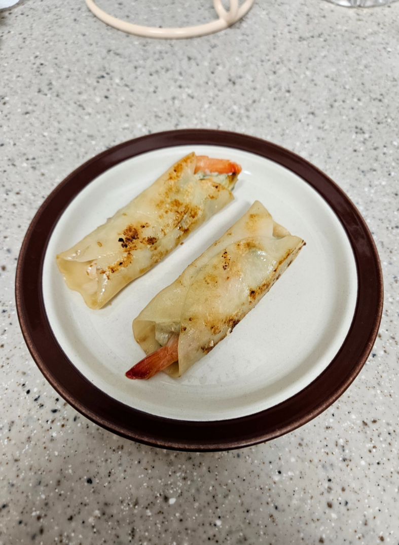 프라이팬에 조리한 비비고 통새우 만두를 접시에 담은 사진 