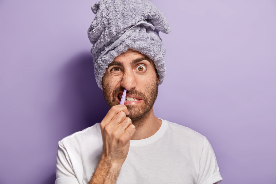 수건을 머리에 두른 수염이 덥수룩하게 난 서양 남성이 핀셋을 이용해서 본인의 콧털을 뽑으며 찡그리고 있는 것을 찍은 사진