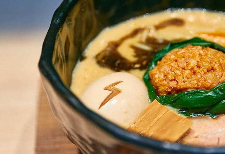 라면 그릇안에 갈색 국물이 있고 된장과 계란이 올라가 있다. 계란에 번개 마크가 찍혀져 있다.