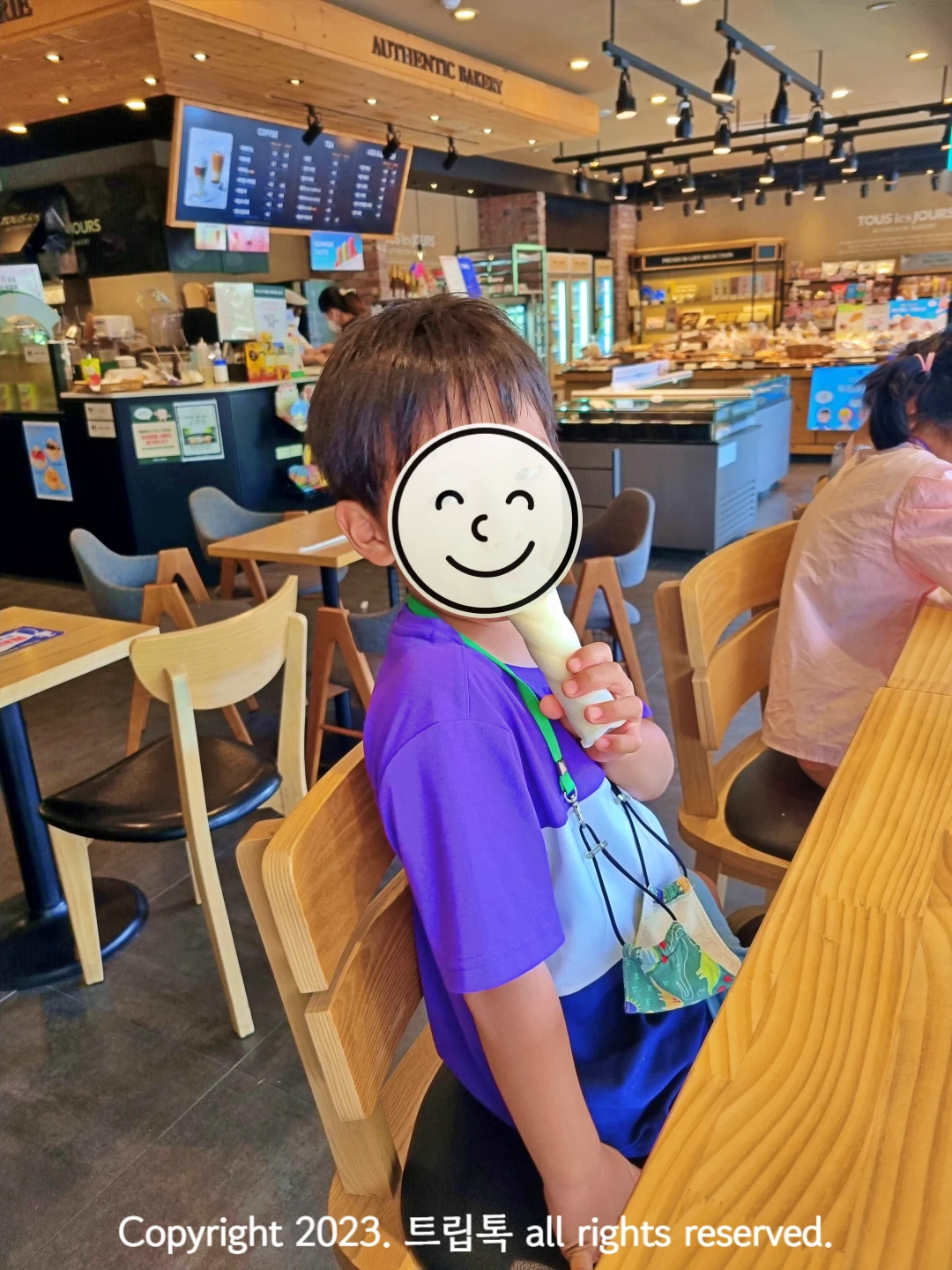 빵이 가득한 빵집에서 아이스크림을 먹는 아이