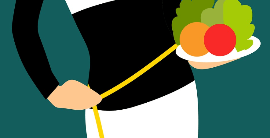 여러가지 채소가 들어 있는 접시를 들고 허리 사이즈를 재고 있는 여성