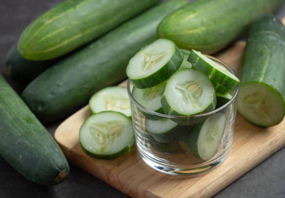 오이 여러개와 잘려져 있는 오이가 컵에 들어있다.