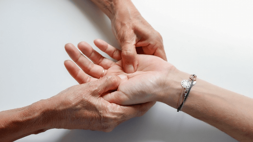 손이 저리는 이유로 손 마사지를 받고 있는 모습