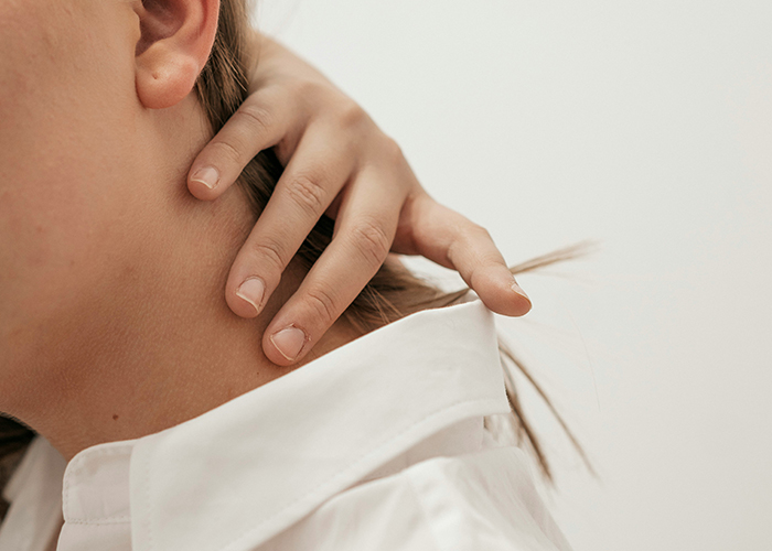 목뒤쪽의 통증으로 통증부위를 만지고 있다