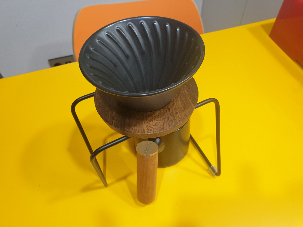 노란 테이블 위에 검은색 드립포트, 세라믹 컵, 드립 스테이션, 세라빅 드리퍼로 구성