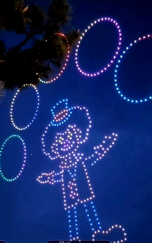 파란 배경 위에 LED 조명으로 사람 모양이 표현된 빛의 설치물. 밝은 원형 조명들이 주변을 둘러싸고 있다.