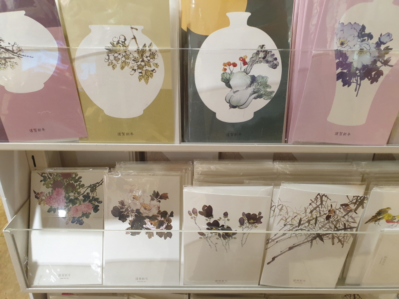 도자기가 그려져 있고 그 안에 꽃이 그려져 있는 민속화 스타일의 연하장.