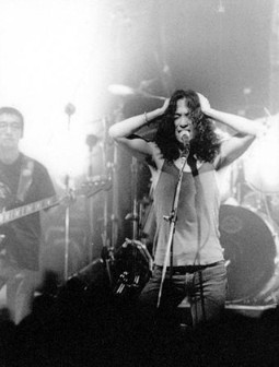 젊은-시절-장발을-한-강산에가-무대에서-양손을-머리에-얹고-노래를-부르는-흑백사진-넌-할-수-있어
